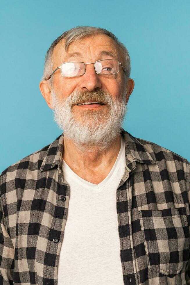 portret gepensioneerd oud Mens met wit haar- en baard gelach opgewonden over- blauw kleur achtergrond foto