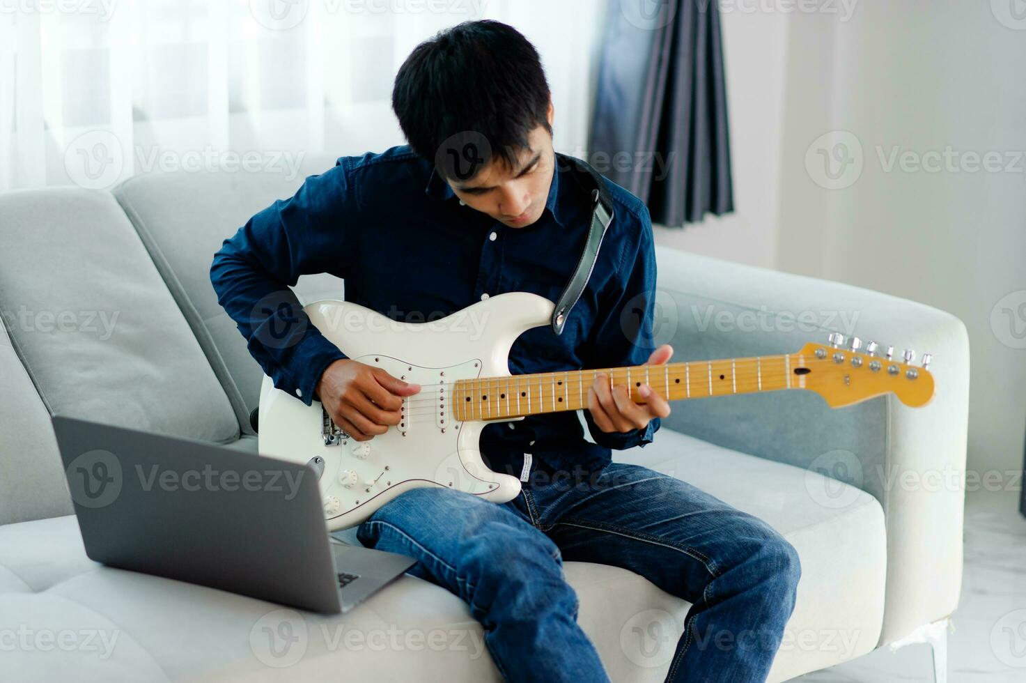 gitarist spelen gitaar Aan sofa Bij huis beoefenen gitaar Bij huis kom tot rust door spelen geregen instrumenten. foto