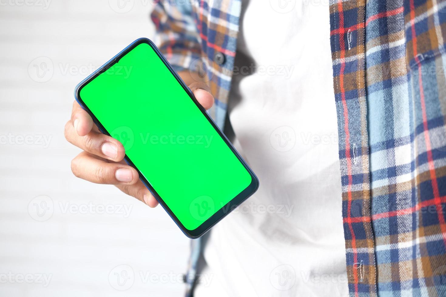 close-up van de hand van de jonge man met behulp van slimme telefoon met groen scherm foto