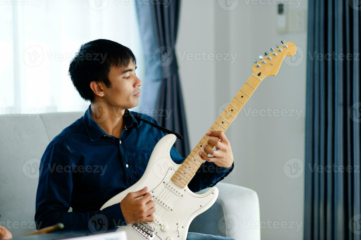 gitarist spelen gitaar Aan sofa Bij huis beoefenen gitaar Bij huis kom tot rust door spelen geregen instrumenten. foto