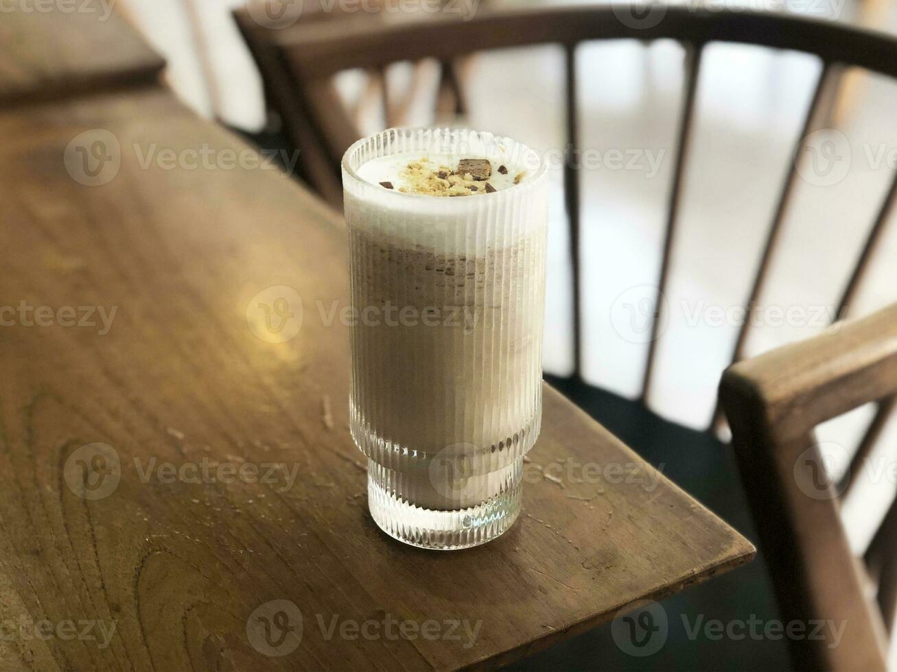 een glas van melk koffie met een sprenkeling van vorstelijk biscuits Aan top foto