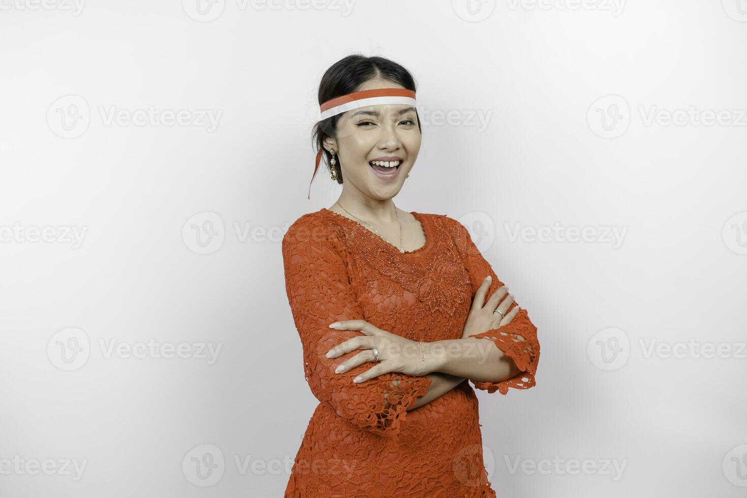 een zelfverzekerd Indonesisch vrouw vouwen haar armen en vervelend rood kebaya en Indonesië's vlag hoofdband naar vieren Indonesië onafhankelijkheid dag. geïsoleerd door wit achtergrond. foto