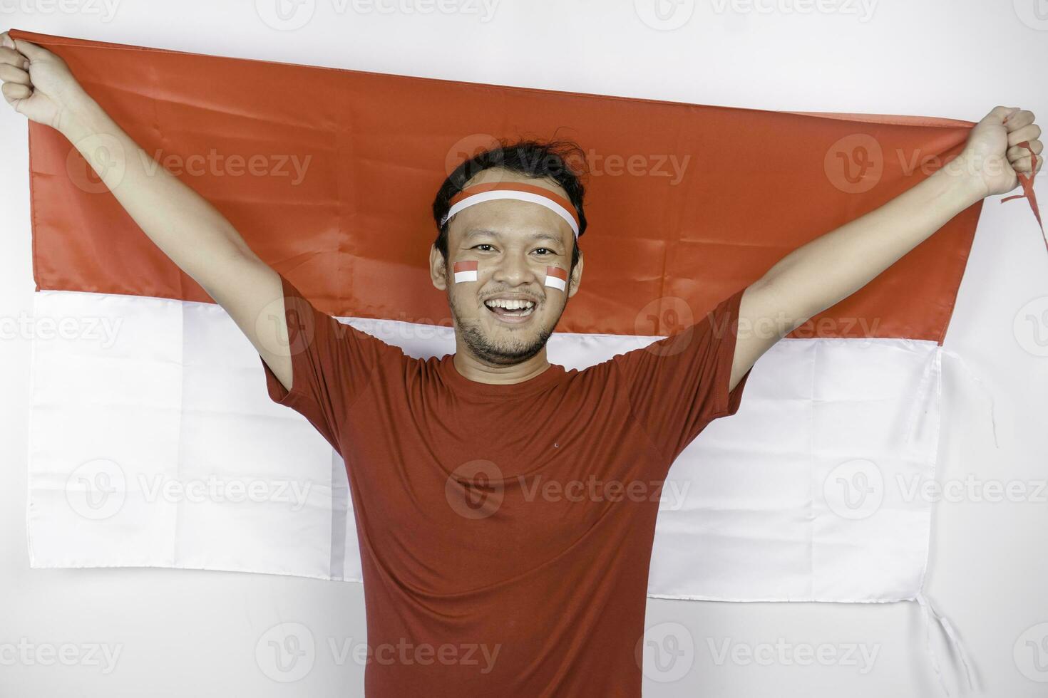 gelukkig glimlachen Indonesisch Mens Holding Indonesië's vlag naar vieren Indonesië onafhankelijkheid dag geïsoleerd over- wit achtergrond. foto