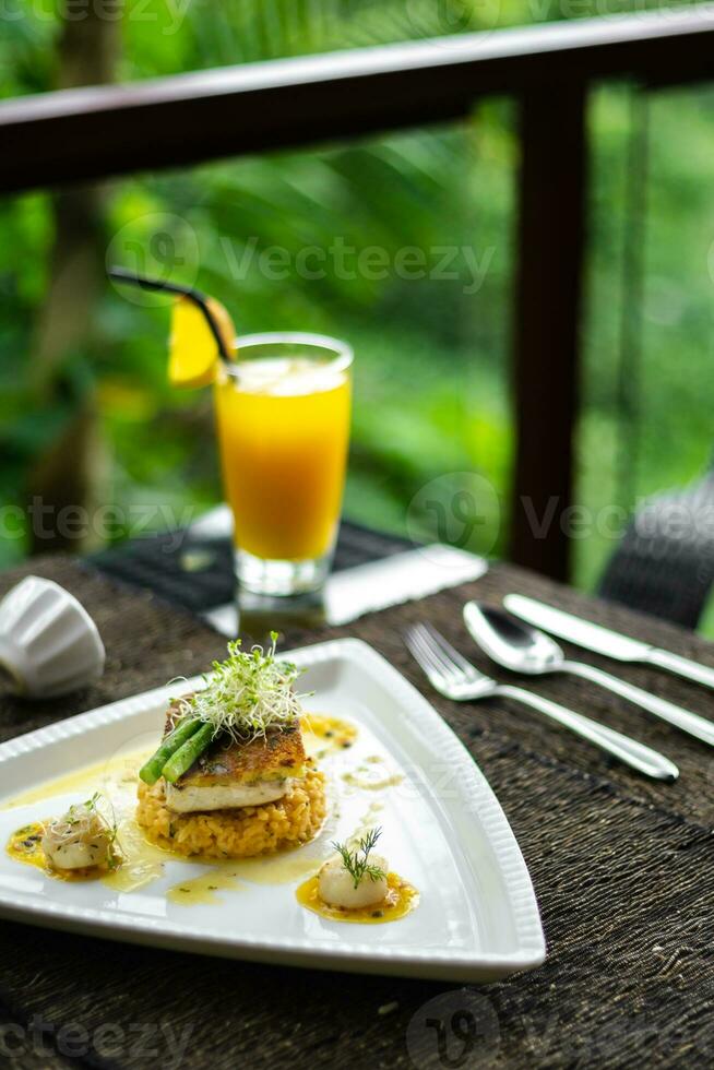 een bord van voedsel Aan een tafel met een glas van oranje sap foto