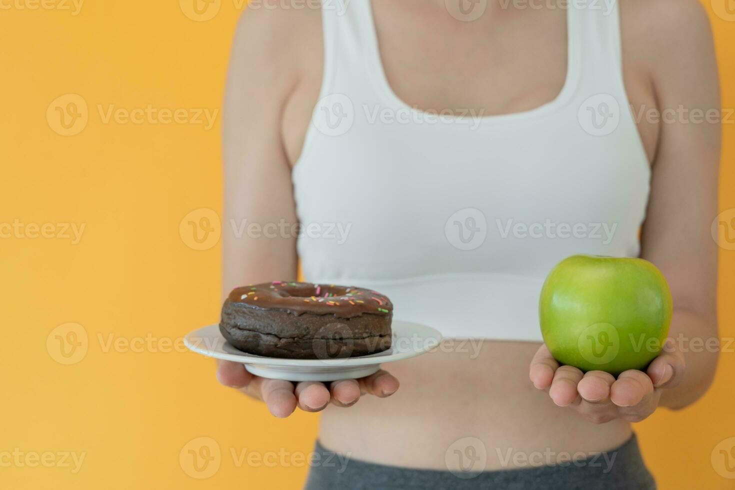 slank lichaam Dames Kiezen gedurende groen appel en chocola donut, vrouw Kiezen groen appel voor eetpatroon. mooi zo gezond voedsel. gewicht verliezen, evenwicht, controle, verminderen dik, laag calorieën, routines, oefening. foto