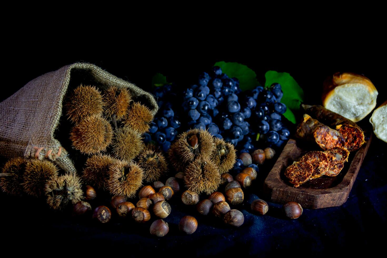 zak met kastanjes, chorizo en bundel van druiven foto