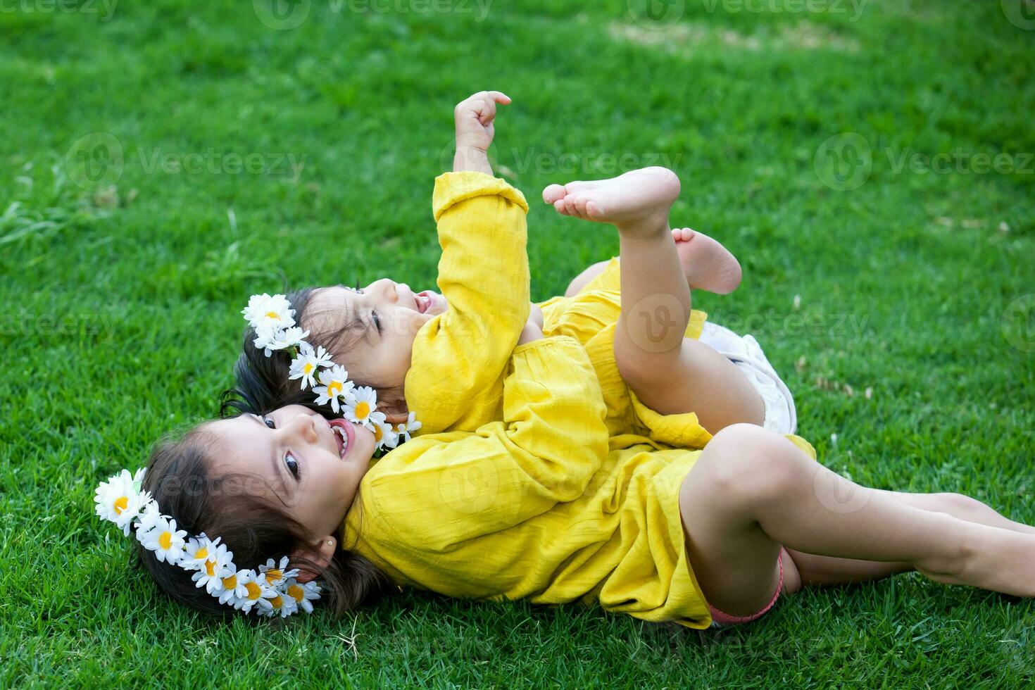 mooi klein zussen gekleed in geel spelen en hebben pret buitenshuis. geluk concept. familie concept foto