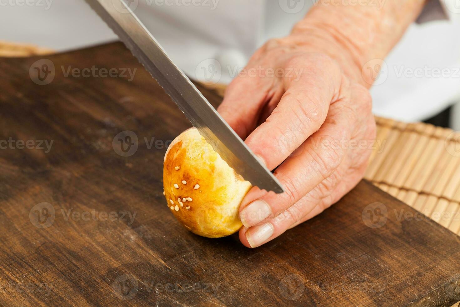 snijdend klein brood broodjes voor mini hamburgers. stap door stap voorbereiding van mini hamburgers. eigengemaakt mini hamburgers voor kinderen of voorgerechten. klein hamburgers. foto