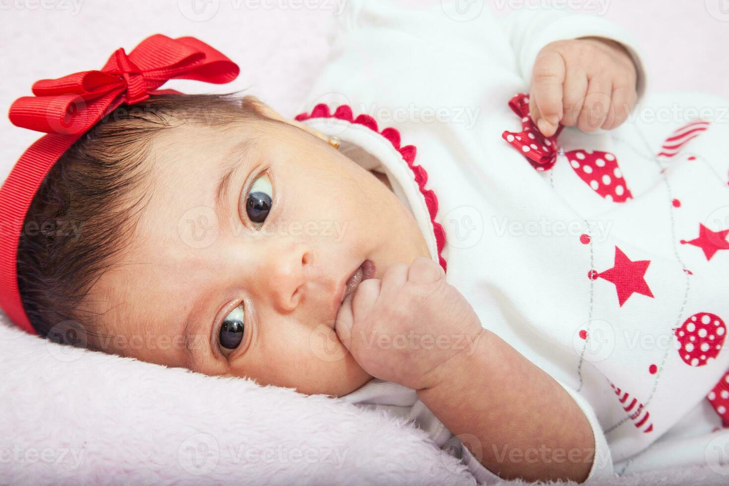 dichtbij omhoog van een zoet een maand baby meisje vervelend een rood en wit Kerstmis t-shirt. foto