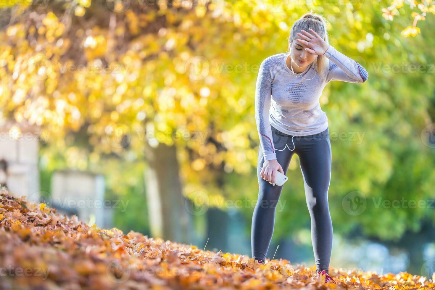 jong vrouw atleet loper moe ademen na rennen in een mooi kleurrijk herfst park foto