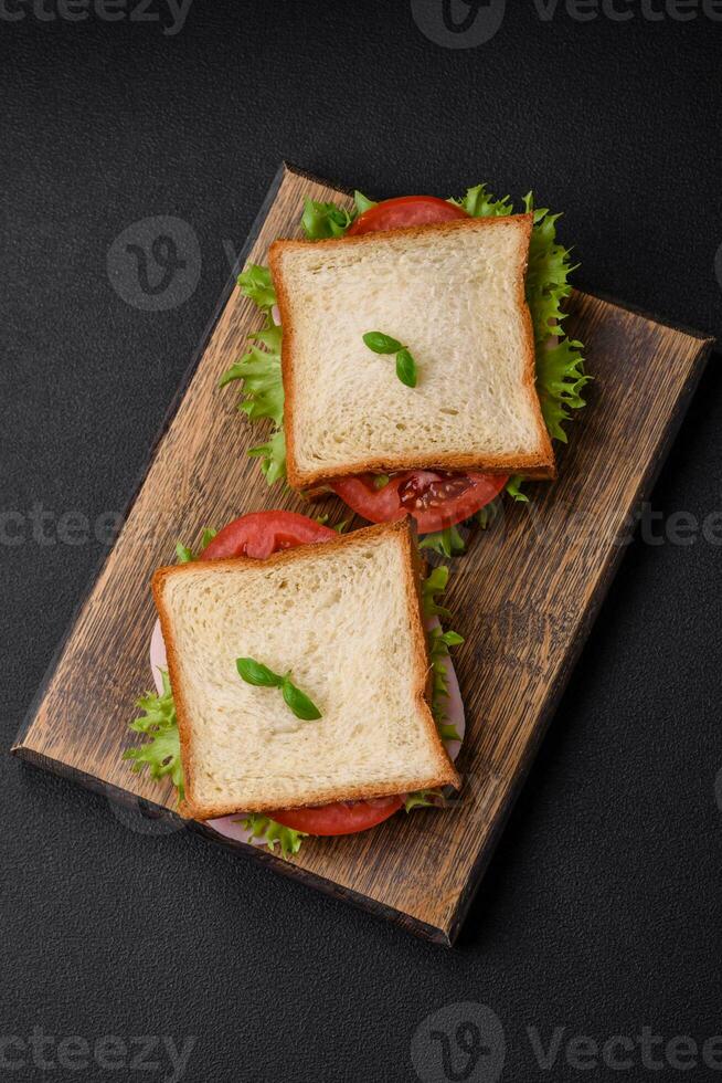 heerlijk belegd broodje met geroosterd brood, ham, tomaten, kaas en sla foto