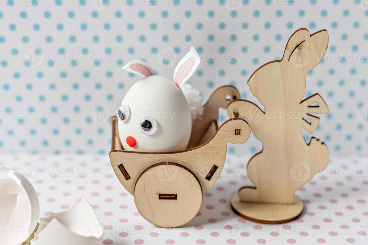 houten konijn dat een kar draagt met een ei met konijnenoren en een muilkorf foto