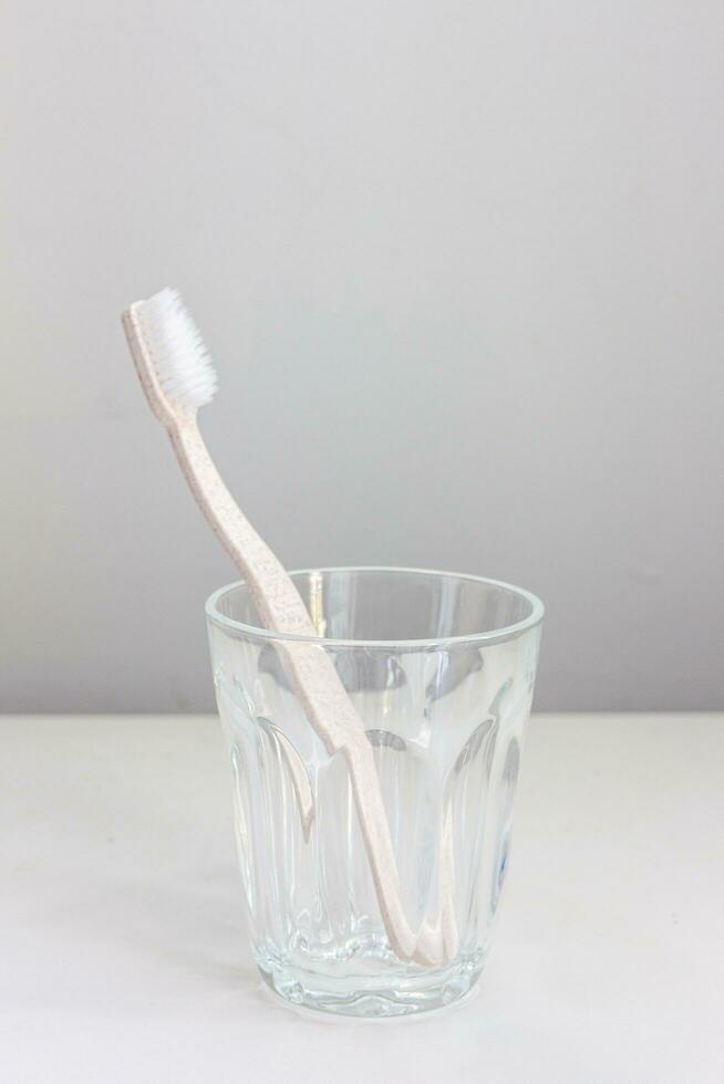 roze tandenborstel in een glas geplaatst Aan een wit achtergrond foto