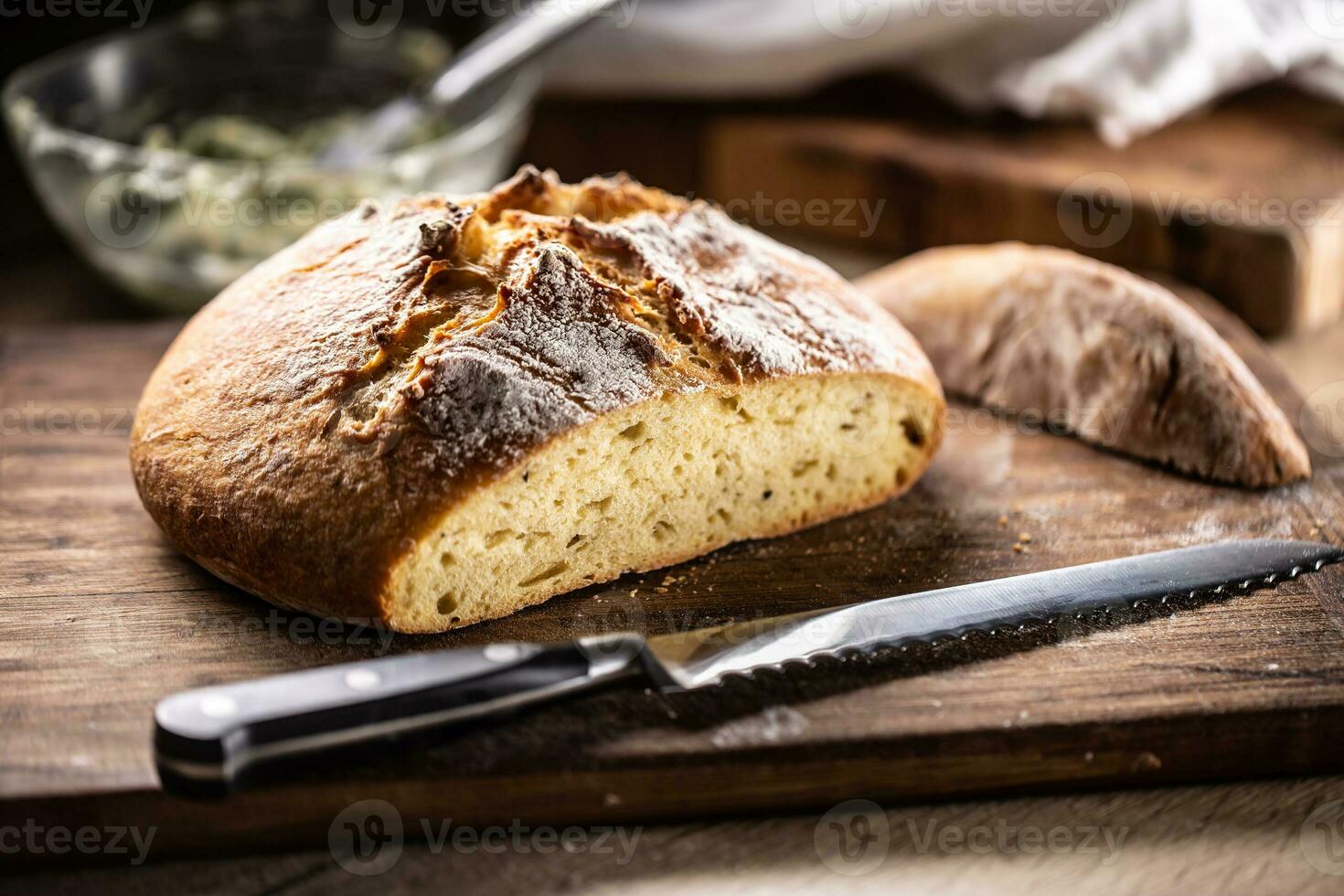 vers gebakken knapperig brood met haar eerste plak besnoeiing uit door een getand mes foto