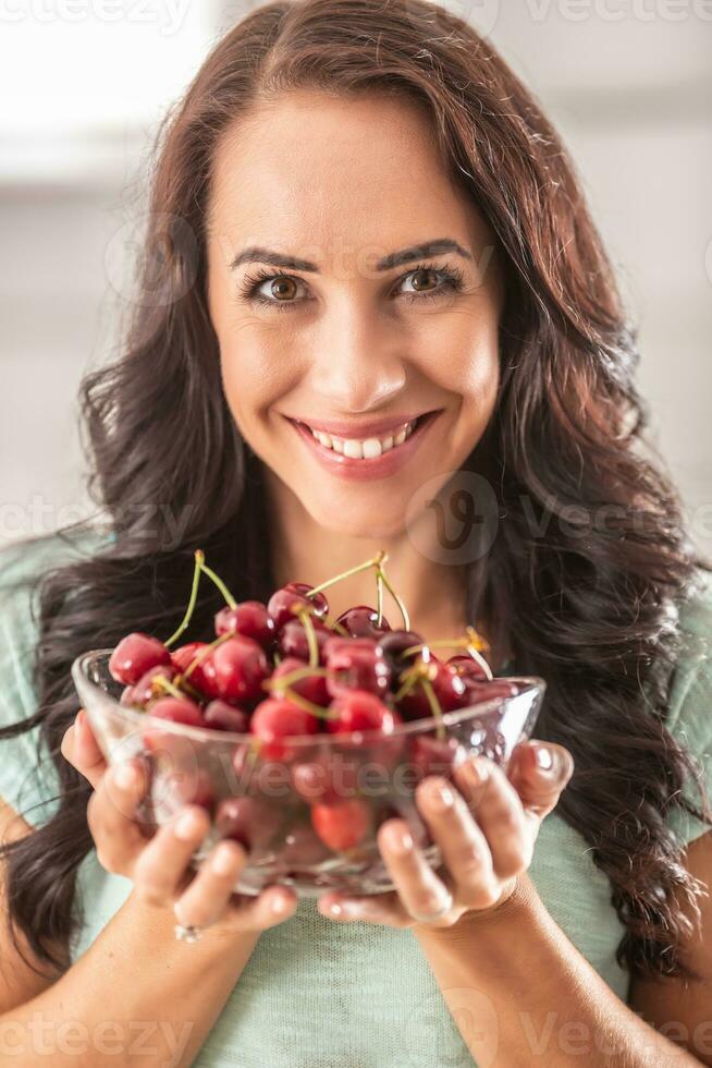 mooi vrouw Holding glas kom vol van fres kersen foto