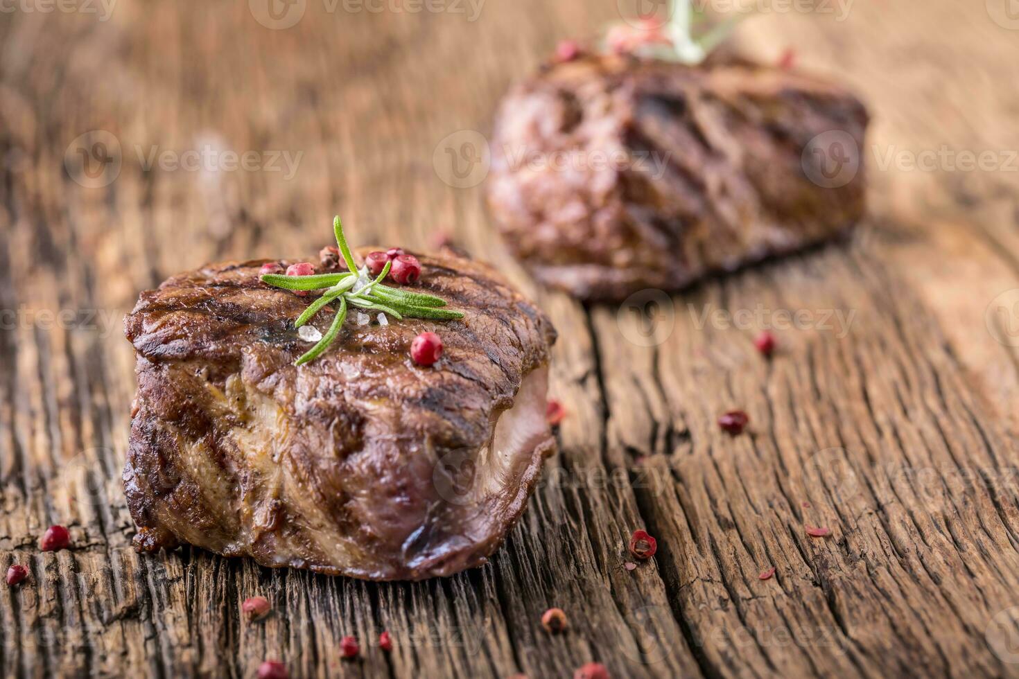 gegrild rundvlees steak met rozemarijn, zout en peper Aan oud snijdend bord. rundvlees lende steak. foto