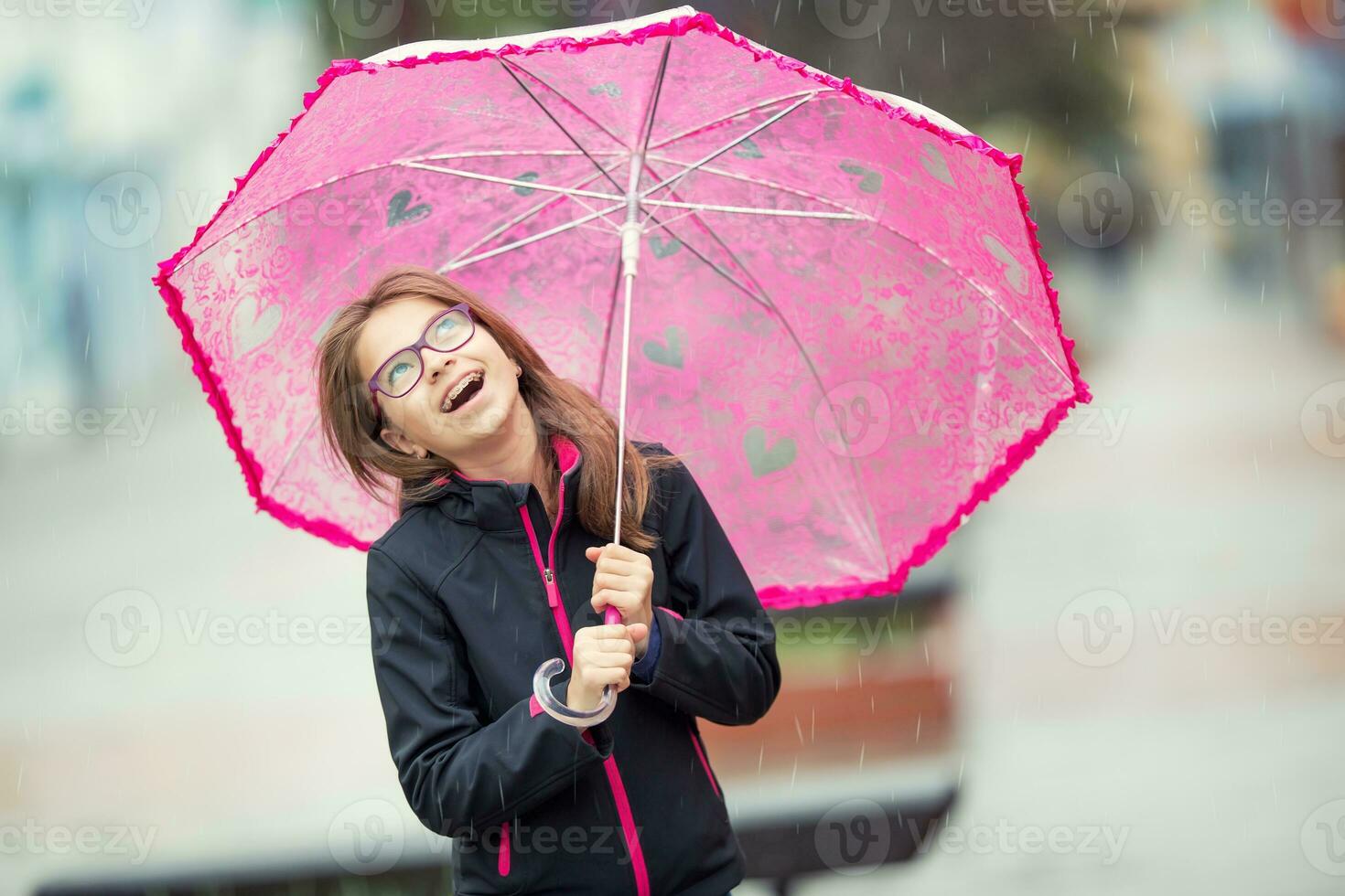 portret van gelukkig mooi jong pre-tiener meisje met roze paraplu onder regen. foto