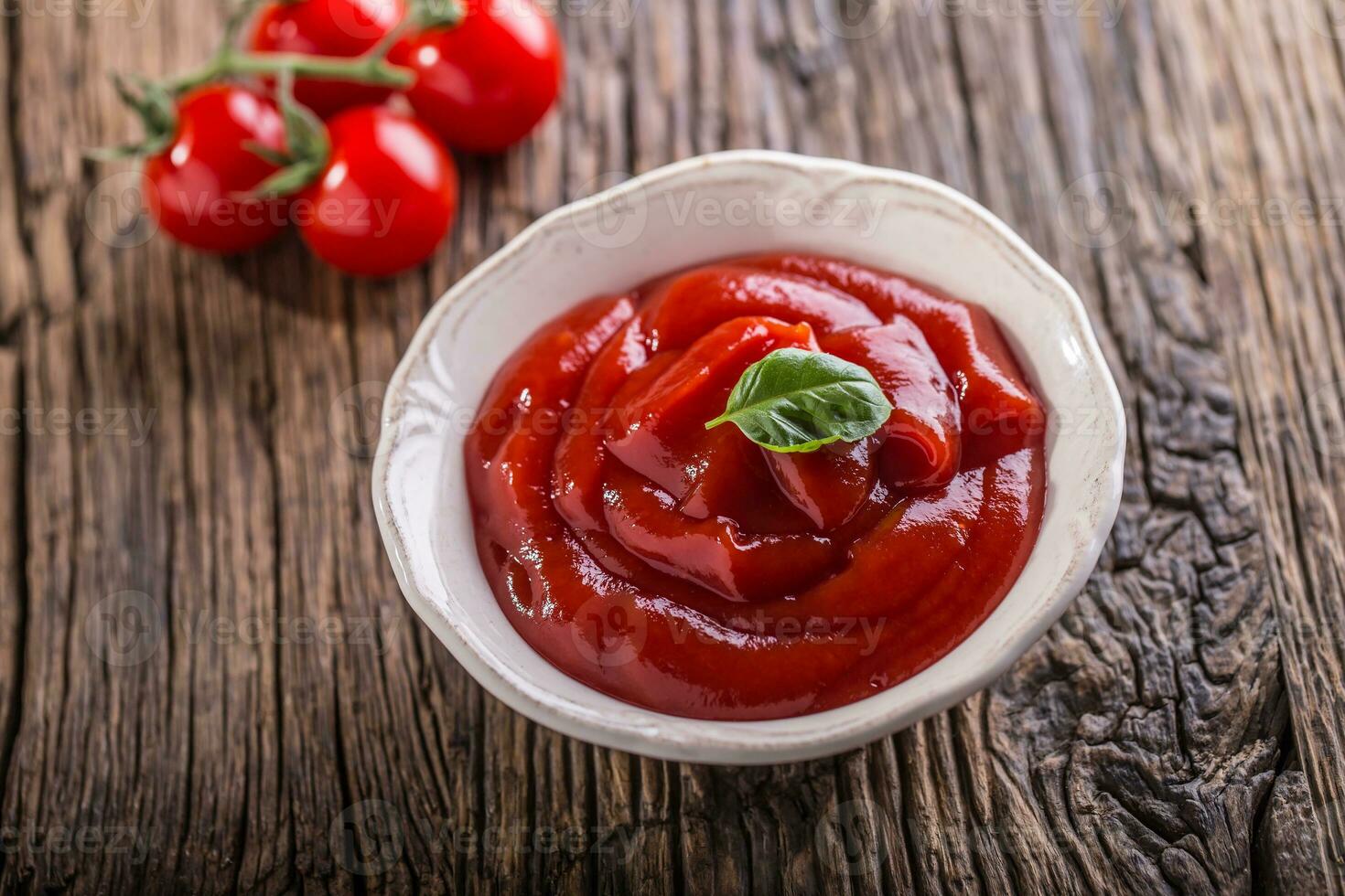 ketchup of tomaat saus in wit kom en kers tomaten Aan houten tafel. foto