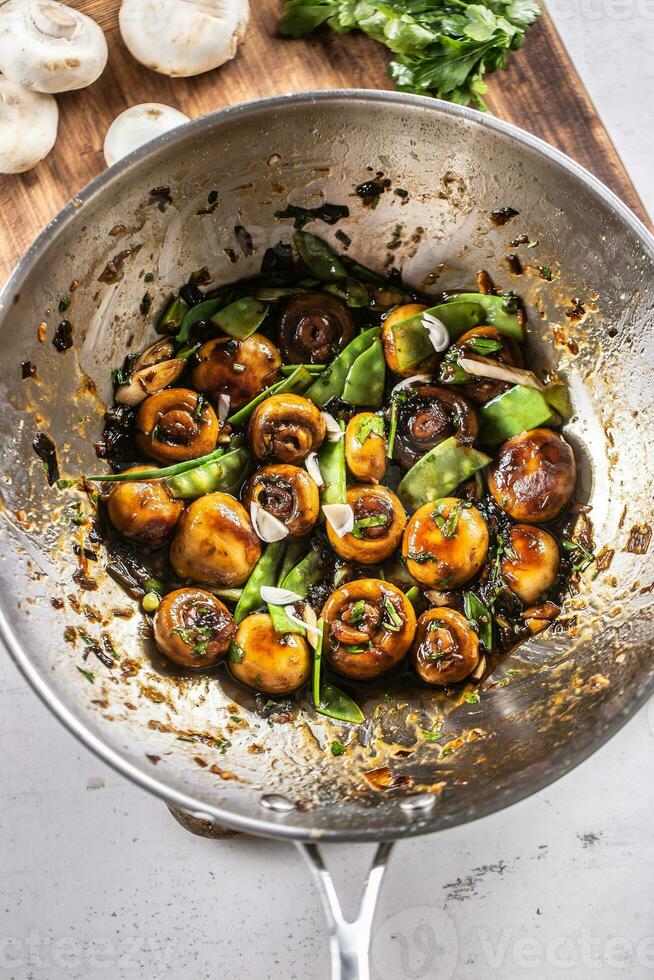 geroosterd champignons in een wok met voorjaar erwten, ui en teriyaki saus foto