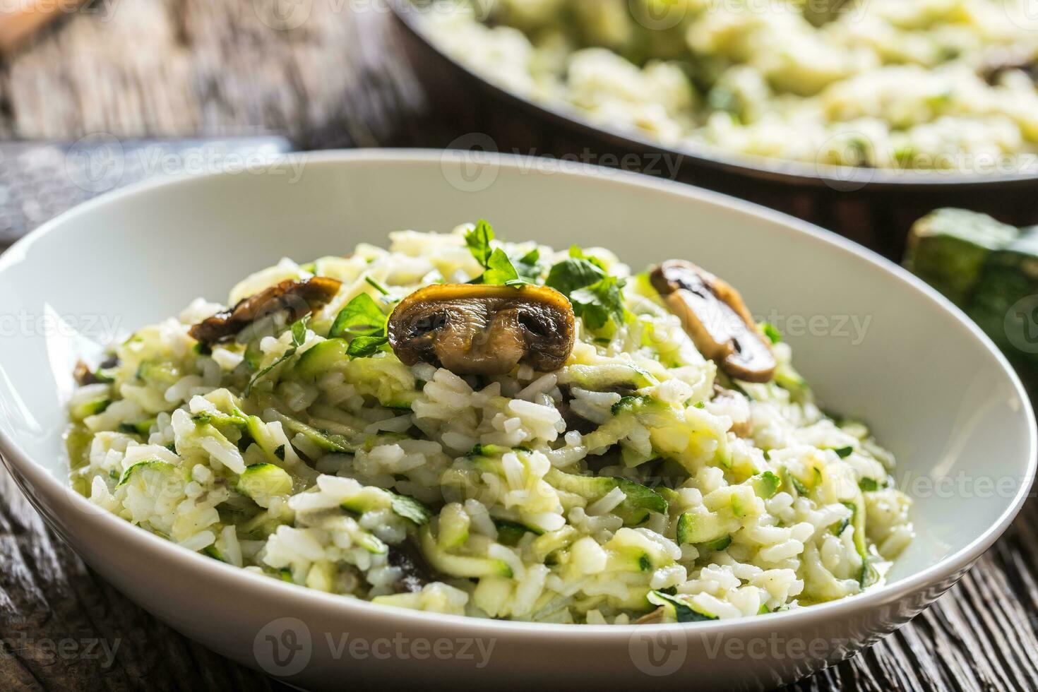 Italiaans risotto courgette champignons en Parmezaanse kaas in wit bord foto