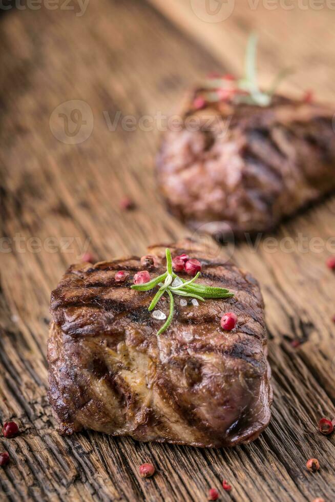 gegrild rundvlees steak met rozemarijn, zout en peper Aan oud snijdend bord. rundvlees lende steak. foto