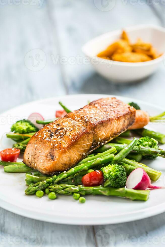 geroosterd Zalm steak met asperges broccoli wortel tomaten radijs groen bonen en erwten. vis maaltijd met vers groente foto