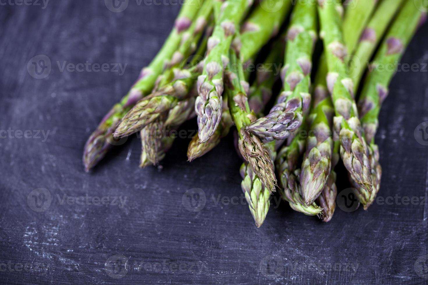 biologische verse rauwe tuin asperges close-up op zwarte bord achtergrond. groene lentegroenten. foto