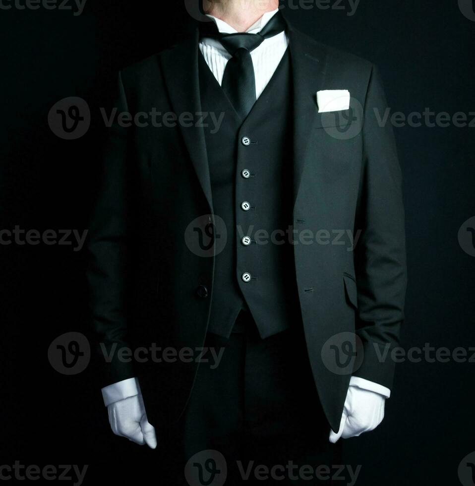 portret van elegant butler in donker formeel pak en wit handschoenen staand Bij aandacht. onderhoud industrie en professioneel gastvrijheid. foto