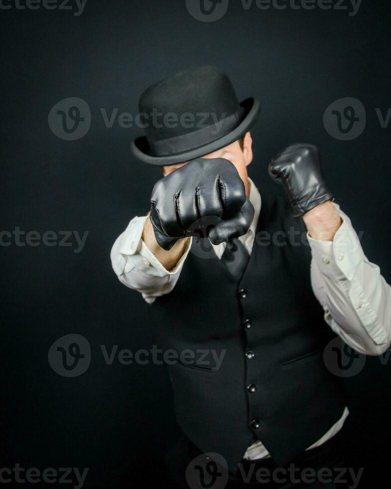 portret van gevaarlijk wijnoogst vechter in hesje en bowler hoed staand in karate houding. gangster in zwart leer handschoenen. foto
