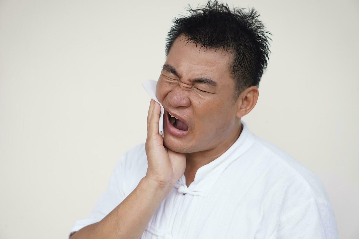 Aziatisch Mens lijdt van pijnlijk kiespijn, gom ontsteking, gebruik hand- naar tintje zijn wang, dichtbij ogen, Open mond. concept, tandheelkundig Gezondheid probleem en Gezondheid zorg. foto