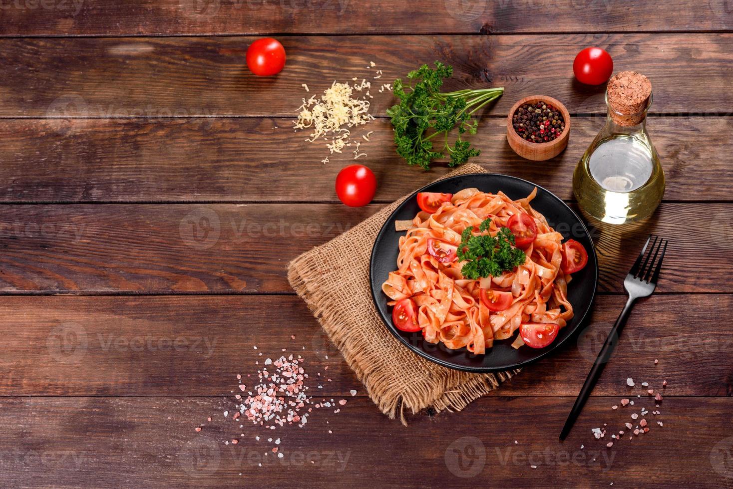 heerlijke verse pasta met tomatensaus met specerijen en kruiden op een donkere achtergrond foto