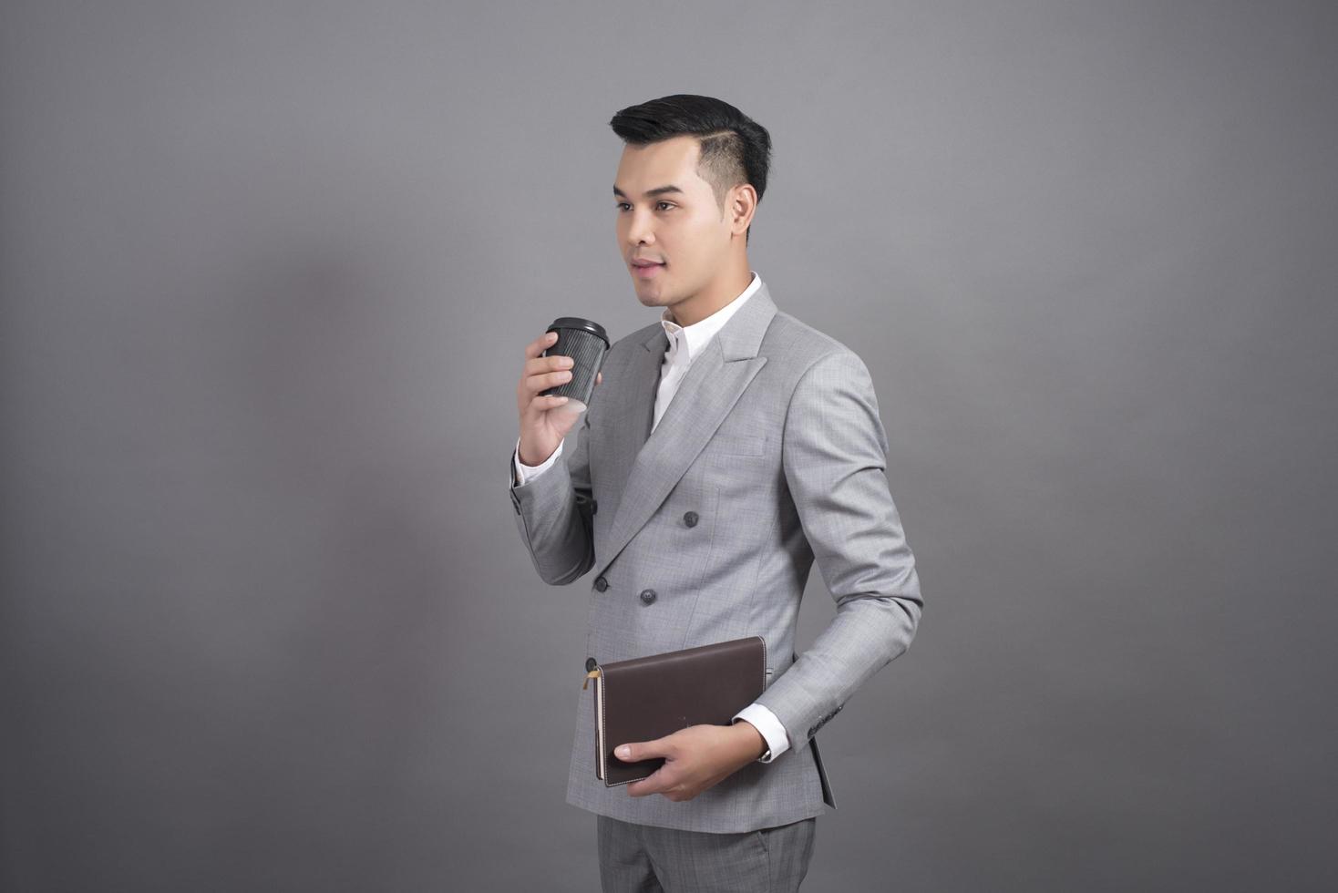 zakenman drinkt koffiepauze, portret in studio grijze achtergrond foto