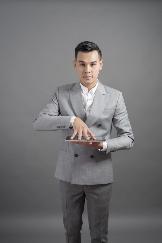 zakenman gebruikt tablet, portret in studio grijze achtergrond foto
