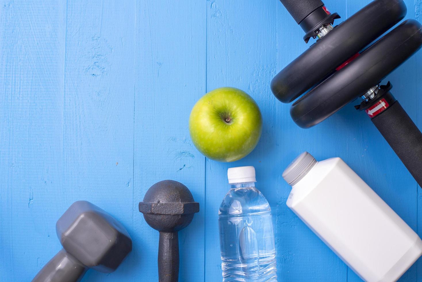 fitnessapparatuur en gezondheidsvoedsel op blauwe houten achtergrond foto