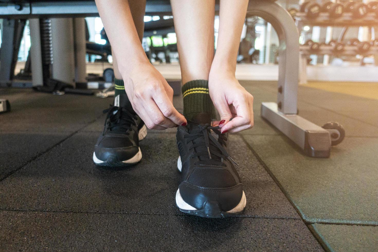 close-up vrouw bindt haar schoen vast in sportschool foto