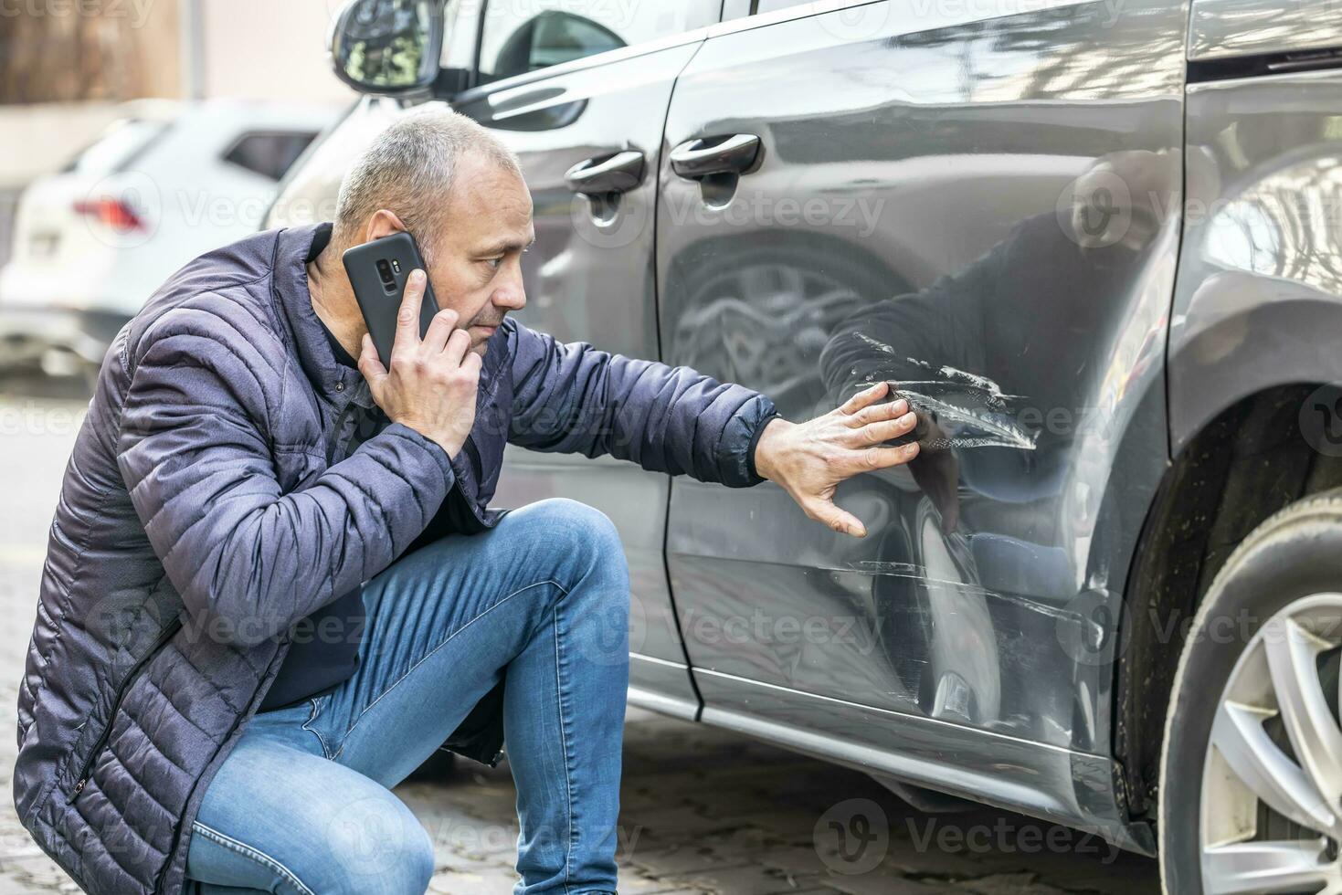een Mens oproepen de verzekering bedrijf of de Politie omdat iemand gesteund in de kant deur van zijn auto in de parkeren veel foto