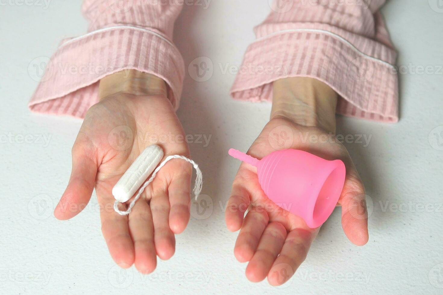 detailopname van een vrouw Holding een keuze van tampon of siliconen menstruatie- kop in haar handen. alternatief ecologisch vrouwelijk hygiëne Product gedurende menstruatie afvalvrij concept foto