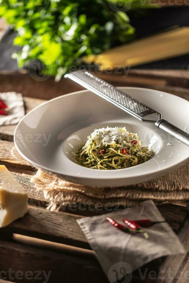 spaghetti aglio e olio met olijf- olie, grieks, basilicum, Parmezaanse kaas kaas, tomaten en pepers geserveerd in een diep bord foto