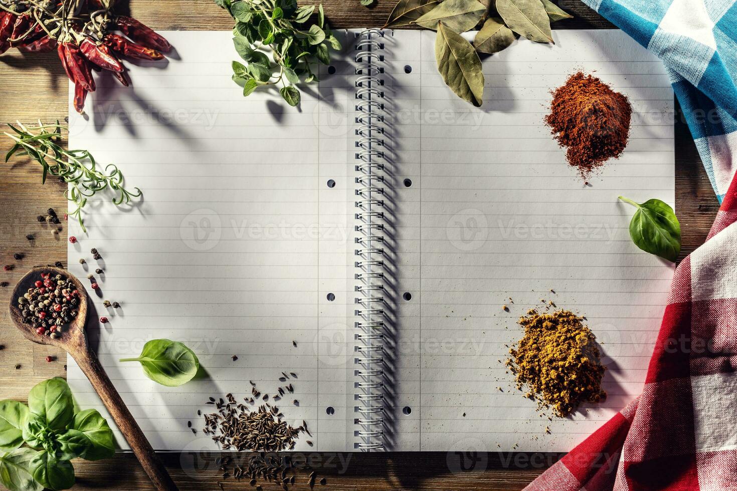 Open notitieboekje met specerijen en kruiden, Chili, oregano, kerrie, basilicum, komijn ,baai blad, en rozemarijn foto