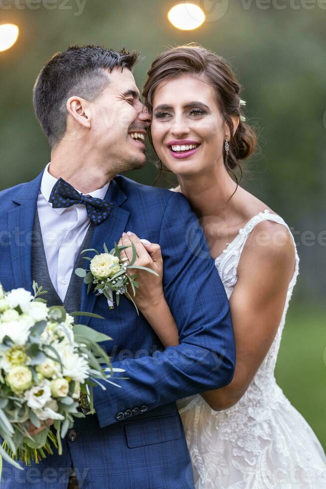 mooi pasgetrouwde paar lacht en houdt elk andere Aan hun bruiloft dag na de ceremonie foto