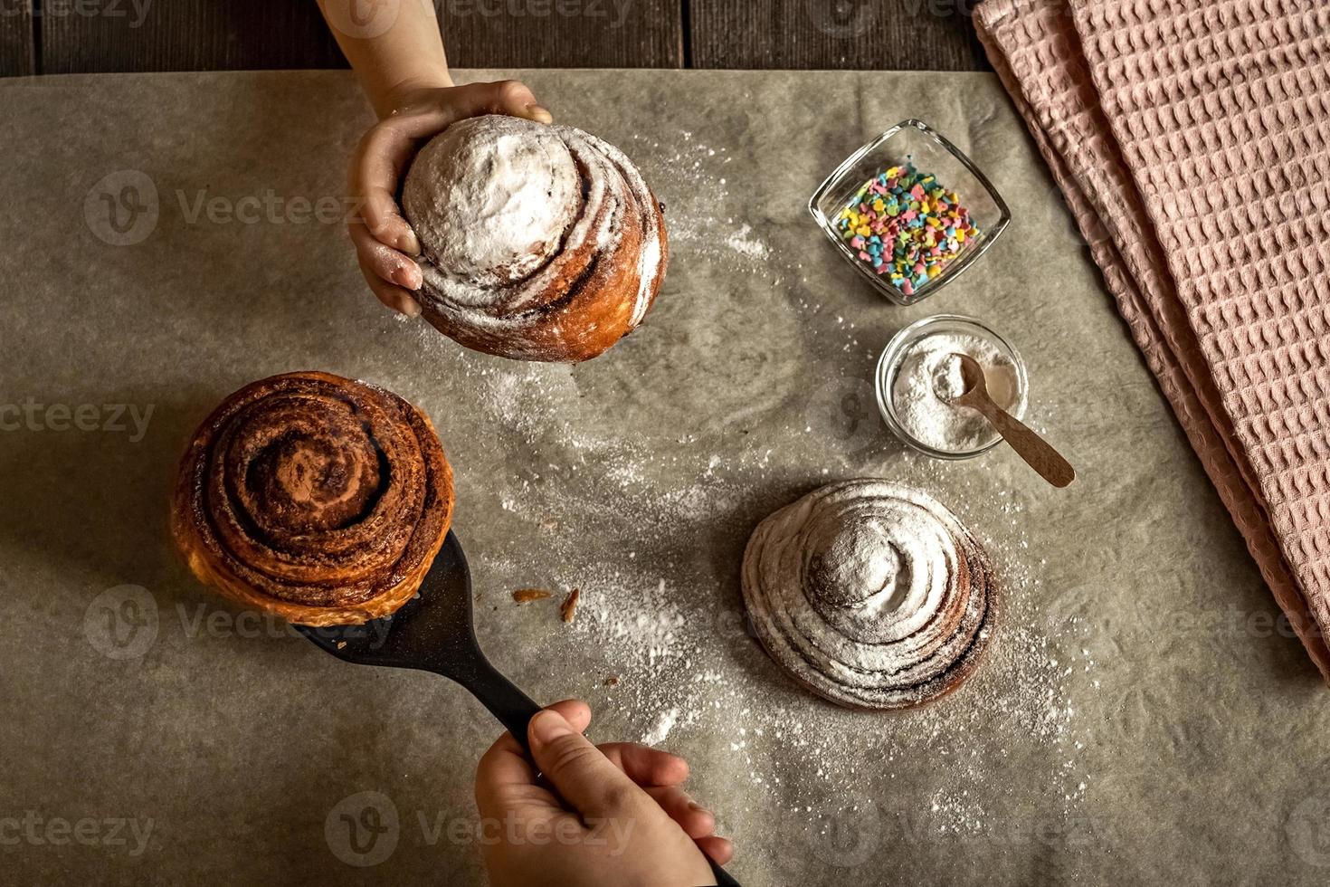 kinderhand pakt een versgebakken kaneelbroodje foto