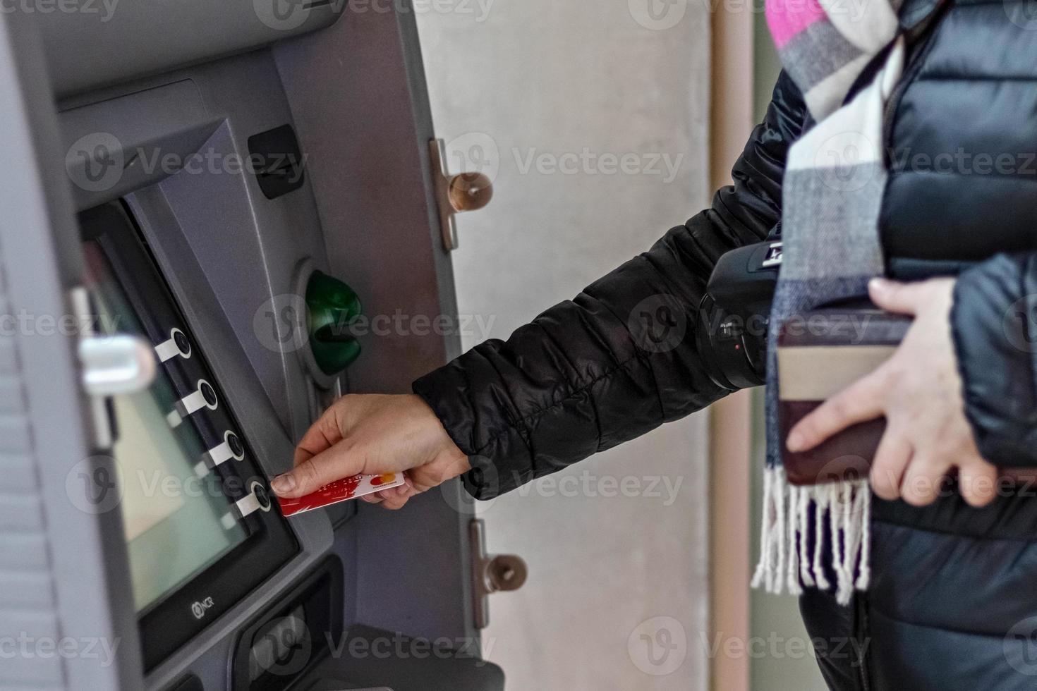 vrouwelijke handen houden een plastic bankcreditcard vast, gebruiken een geldautomaat foto