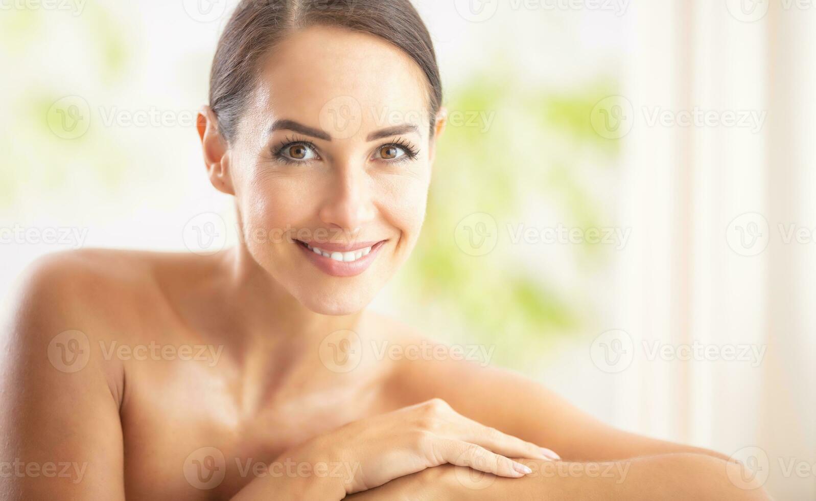 mooi portret van jong volwassen vrouw met schoon huid zonder bedenken zittend in een schoonheid salon en op zoek in de camera. spa huidsverzorging welzijn en schoonheidsmiddelen concept foto