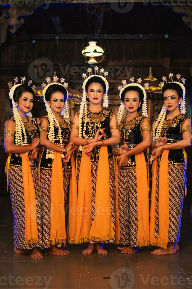 een groep van Javaans dansers staand met hun vrienden terwijl vervelend geel kostuums en sjaals foto