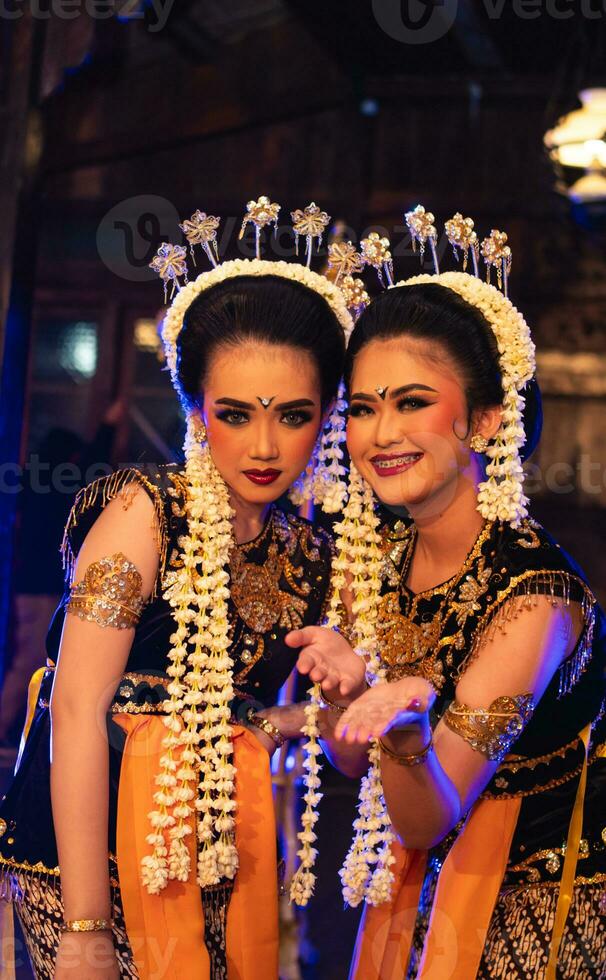 twee Javaans dansers in geel sjaals nemen afbeeldingen met belachelijk gezichten foto