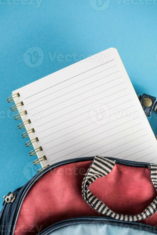 school- rugzak en notitieboekje Aan blauw achtergrond foto