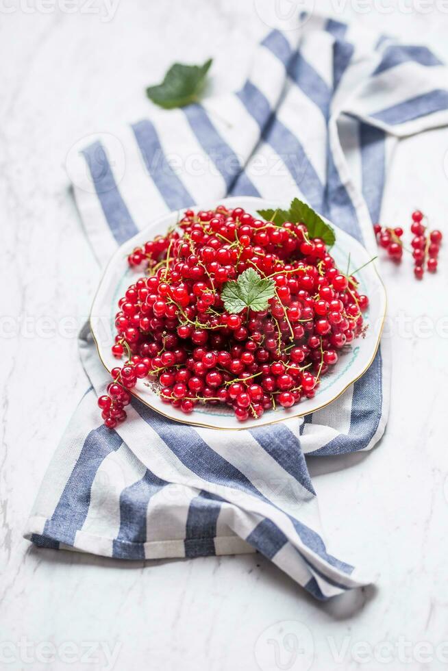 bord vol van vers rood krenten Aan marmeren tafel foto