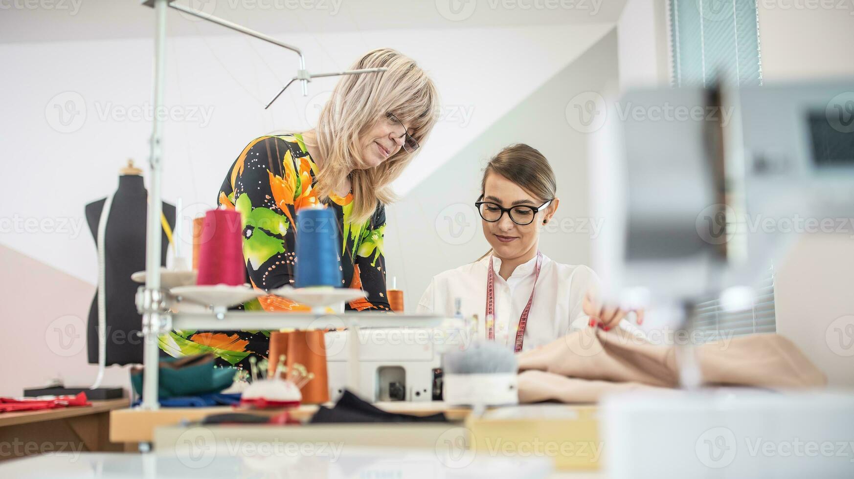 twee generaties van vrouw kleermakers samenwerken Bij werk in de klein werkplaats foto