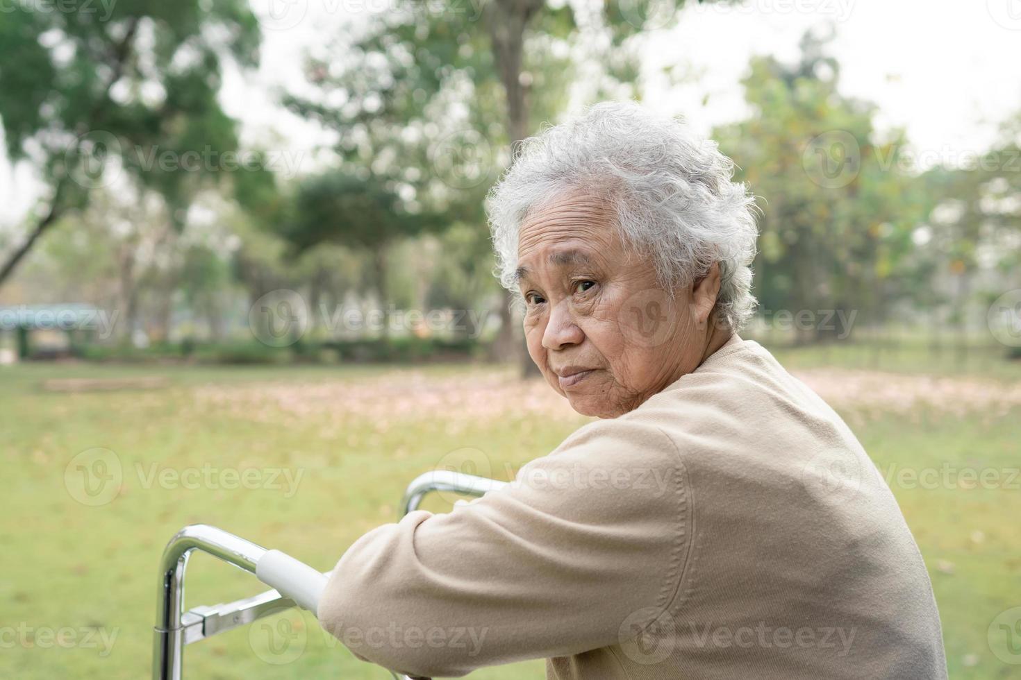 aziatische senior of oudere oude dame vrouw gebruikt rollator met een sterke gezondheid tijdens het wandelen in het park in een fijne frisse vakantie. foto