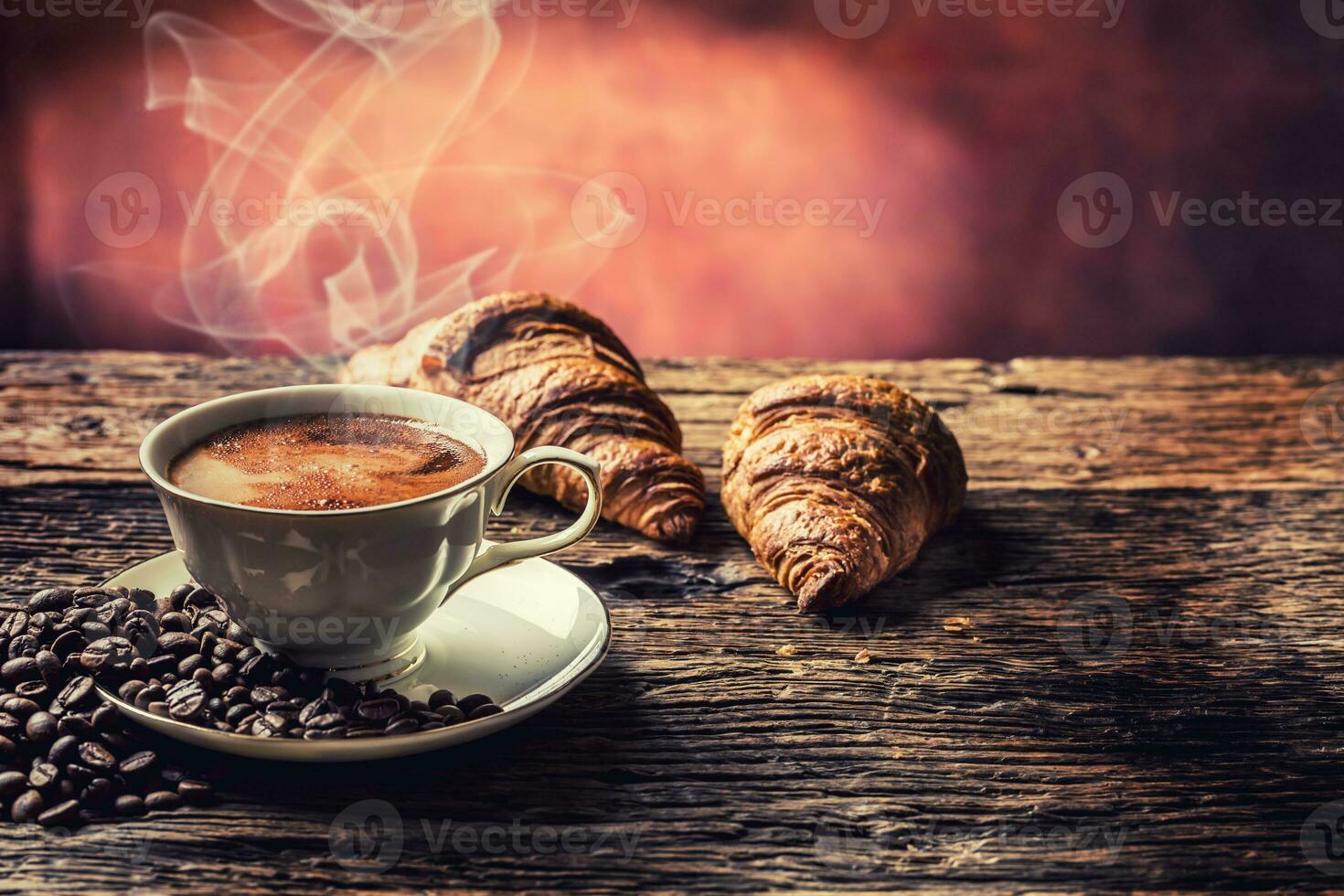 koffie. kop van koffie croissants en koffie bonen. wijnoogst kop en oud eik tafel foto